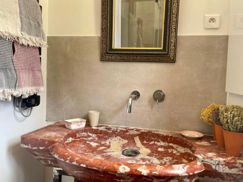 y baño con lavabo de piedra y espejo. en Ferme d'hôtes de Pouzes, en Pézenes-les-Mines