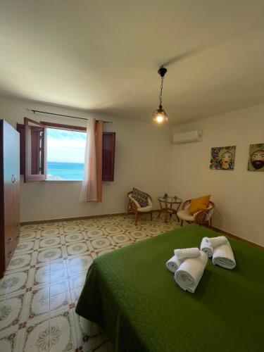 a bedroom with a green bed with a view of the ocean at Appartamento L'Agnuni in Castellammare del Golfo