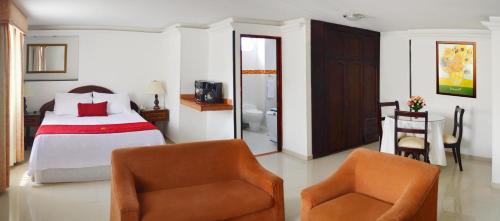 a bedroom with a bed and two chairs at Hotel Plaza Versalles in Cali