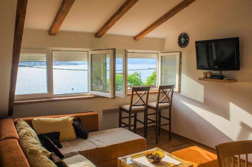a living room with a couch and a tv and windows at Sunny Bay Apartments in Kotor