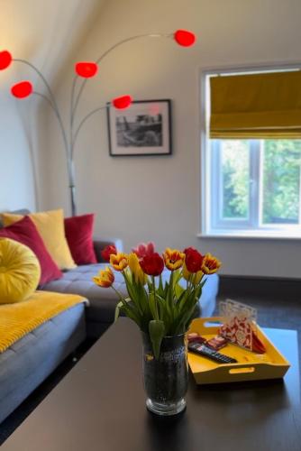 a living room with a vase of flowers on a table at Green Corner Villa - Walls Hill - Cosy Luxury Apartment in Central Torquay with Free Parking & EV in Torquay