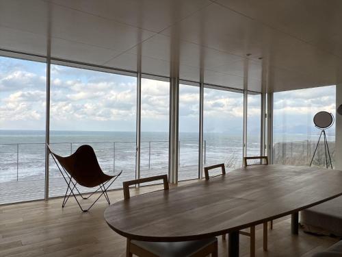 a room with a table and chairs and the ocean at Cliff House MORAI - Vacation STAY 14408 in Ishikari