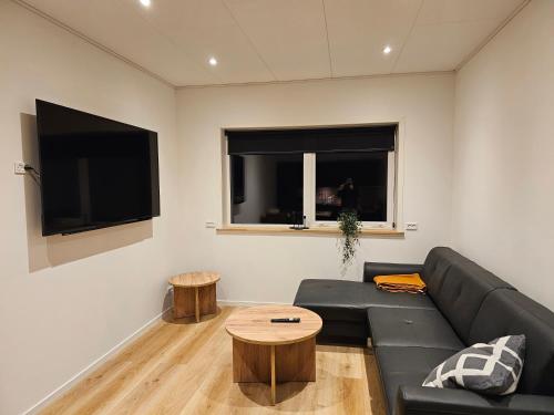 a living room with a black couch and a table at New flat with hot tub - No2 in Oyndarfjørður