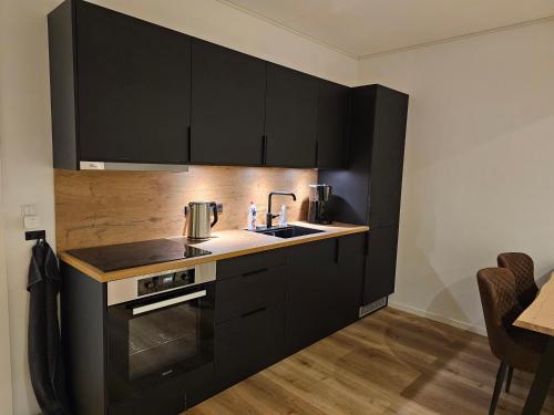 una cocina con armarios negros y fregadero en New flat with hot tub - No2, en Oyndarfjørður