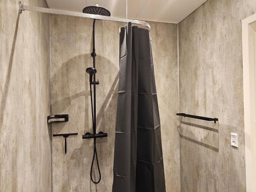 y baño con ducha con cortina negra. en New flat with hot tub - No2, en Oyndarfjørður