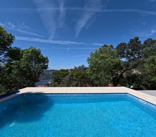 a swimming pool with blue water and trees in the background at Casa de Pinheiral in Baião