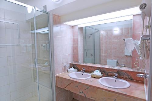 ein Badezimmer mit zwei Waschbecken und einer Glasdusche in der Unterkunft Royal Islander Club Resort La Plage in Lowlands