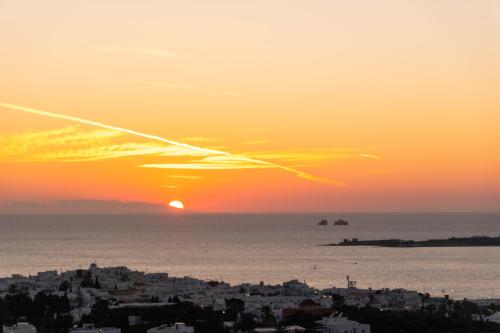 a sunset over the ocean and a city at Panos Luxury Suite in Parikia