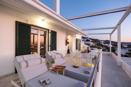 a balcony with white chairs and a table at Panos Luxury Suite in Parikia