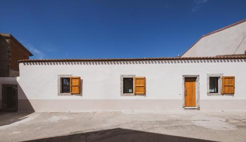 un edificio bianco con porte e finestre in legno di Binzas betzas Agriturismo a Sedilo
