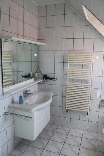 a white bathroom with a sink and a mirror at Ferienwohnung Wegmann in Borkum