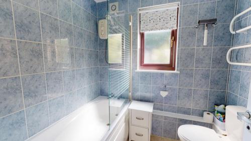 a blue tiled bathroom with a tub and a sink at 35 Strawberry Hill, Tolroy Manor in Hayle