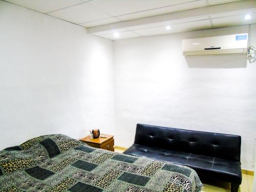 Un dormitorio con una cama y una silla de cuero negro en Comodo y Practico departamento en La Rioja
