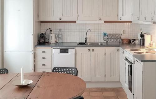 a kitchen with white cabinets and a wooden table at 3 Bedroom Stunning Home In Simrishamn in Simrishamn