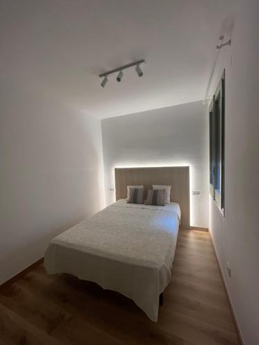 una camera bianca con un grande letto con lenzuola bianche di Racó de Mar a Palamós