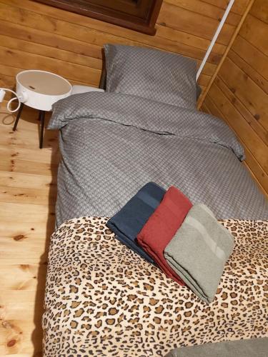 a bed with a leopard print sheets and a blanket at Wakacyjny domek - Łaś Ogrody in Rzewnie