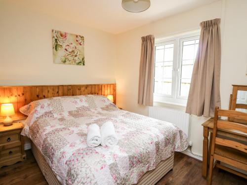 a bedroom with a bed with two white towels on it at Primrose Cottage in Llandrindod Wells