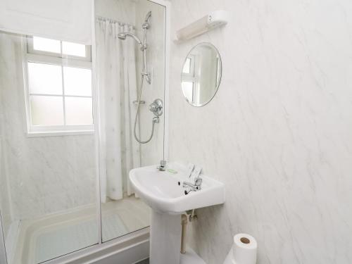 a white bathroom with a sink and a shower at Primrose Cottage in Llandrindod Wells