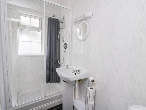 uma casa de banho branca com um lavatório e um chuveiro em Honeysuckle Cottage em Llandrindod Wells