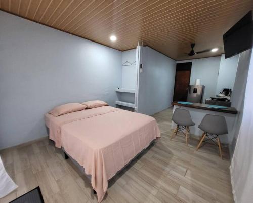 a bedroom with a bed and two chairs and a kitchen at MILA Apartments #4 in Tamarindo