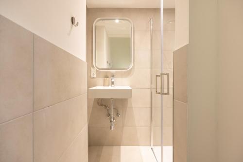 a bathroom with a sink and a shower with a mirror at Great 2-room apartment in Berlin