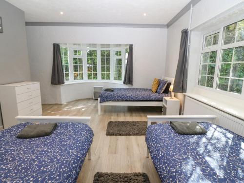 due letti in una stanza con due finestre di Mill House Cottage a Pwllheli