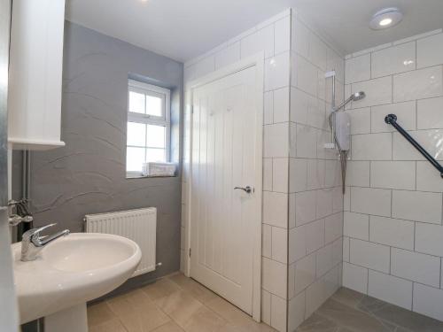un bagno bianco con lavandino e doccia di Mill House Cottage a Pwllheli