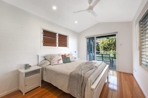 a white bedroom with a bed and a window at 2 6 Teal Street Peregian Beach in Peregian Beach