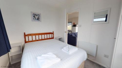 um quarto com uma cama branca com lençóis brancos em B44 Sea Urchin, Riviere Towans em Hayle