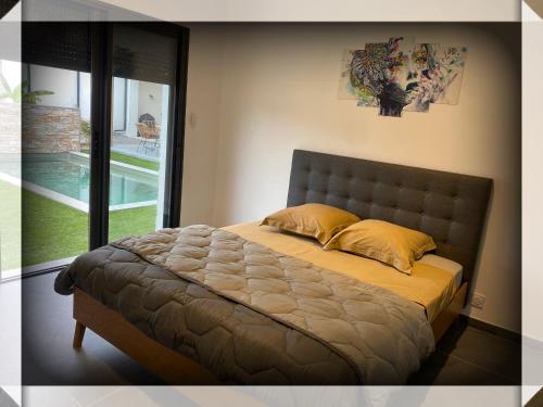 Ce lit se trouve dans une chambre avec vue sur la piscine. dans l'établissement VILLA Paolo, à Saint-Christol-lès-Alès