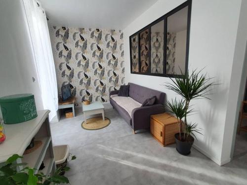 un salon avec un canapé violet et une plante dans l'établissement Roanne centre, appartement refait à neuf., à Roanne