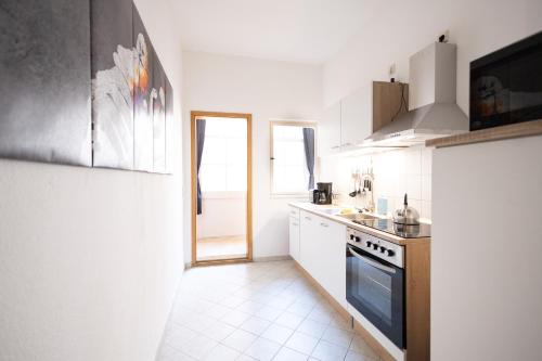 a kitchen with white cabinets and a stove top oven at Apartments an der Oper - Innenstadt - Zentral - Küche - Wifi - Powered by Ko-Living in Halle an der Saale