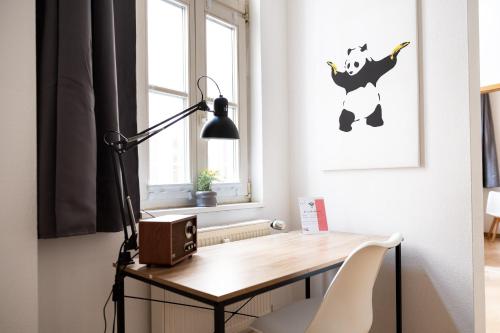 a desk in a room with a lamp and a picture at Apartments an der Oper - Innenstadt - Zentral - Küche - Wifi - Powered by Ko-Living in Halle an der Saale