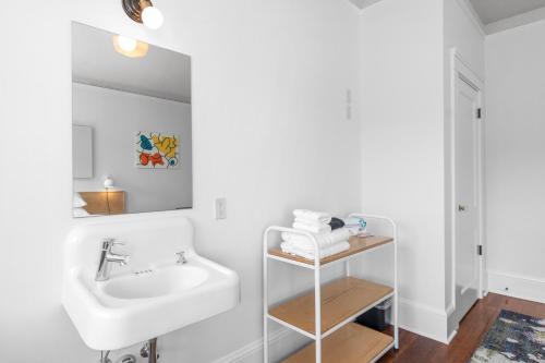 a white bathroom with a sink and a mirror at Norblad Hotel in Astoria, Oregon
