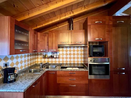 a kitchen with wooden cabinets and stainless steel appliances at Casa Martina - A quiet home by the lake in Colico