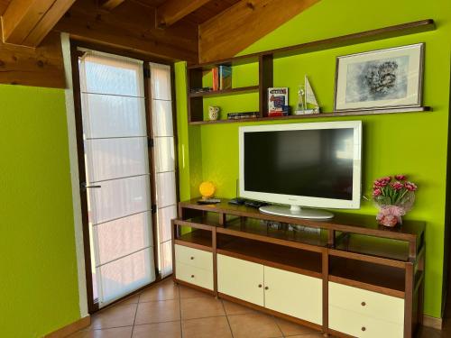 un soggiorno con TV su una parete verde di Casa Martina - A quiet home by the lake a Colico