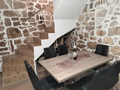 a dining room with a stone wall and a wooden table and chairs at Kuća Get in Betina