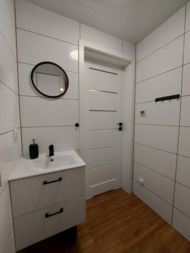 W białej łazience znajduje się umywalka i lustro. w obiekcie Domki na Stoku w Wiśle
