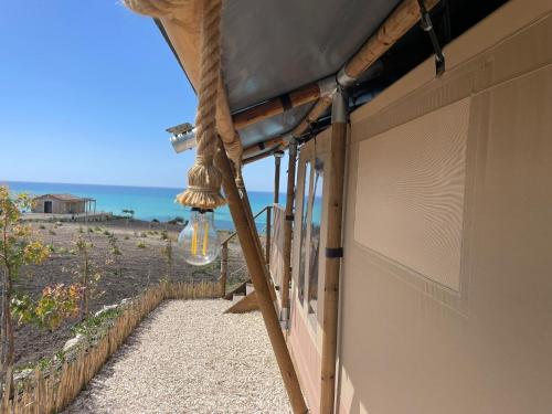 a room with a balcony with a view of the ocean at Tendu' Punta Bianca Glamping Camp in Palma di Montechiaro