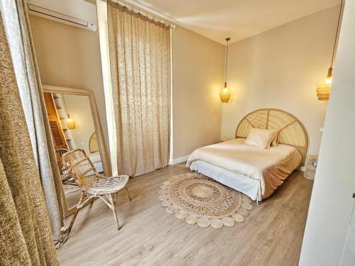 1 dormitorio con cama, silla y espejo en L'île rousse, hypercentre à 100 m de la plage en LʼÎle-Rousse