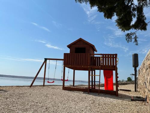 a playground with a swing set on the beach at Family Villa Tiffany&more in Barić Draga