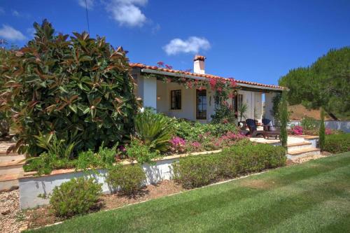 una pequeña casa con un gran arbusto delante de ella en Quinta Casa May en Budens