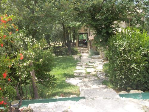a stone path in a garden with trees and flowers at Agriturismo Fontenuova in Saturnia