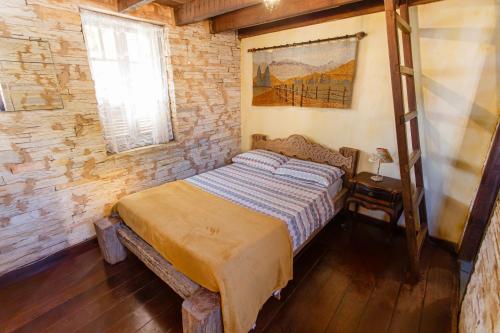 a bedroom with a bed in a brick wall at Chalé de Pedra - Hospedaria in São Thomé das Letras