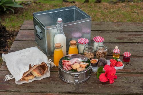 een picknicktafel met een mand met eten en een fles melk bij Pico do Refúgio - Casas de Campo in Ribeira Grande