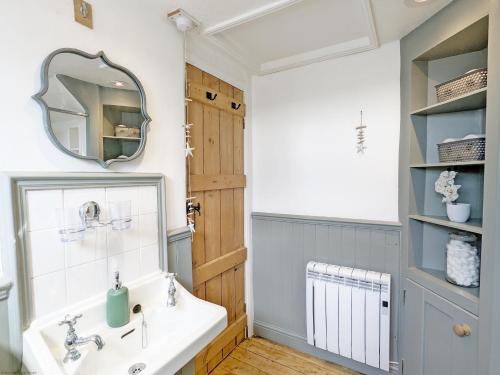 a bathroom with a sink and a mirror at Piemans Cottage in Pulborough