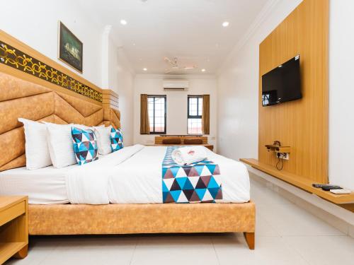 a bedroom with a large bed and a flat screen tv at Hotel Galaxy Opp Surat Railway Station in Surat