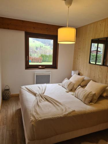 une chambre avec un grand lit blanc avec une fenêtre dans l'établissement Luxury holidays apartment Praz sur Arly, à Praz-sur-Arly