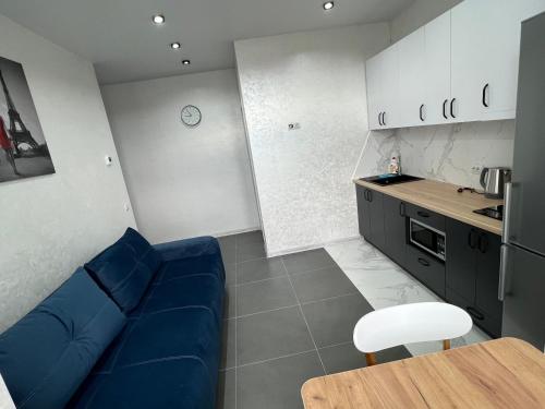 a living room with a blue couch and a kitchen at Apartment for you in Ivano-Frankivsʼk