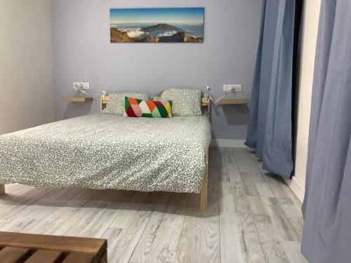 um quarto com uma cama e uma almofada num piso de madeira em Tierritas Village (Ventanas del Atlántico 2) em Santa Cruz de la Palma